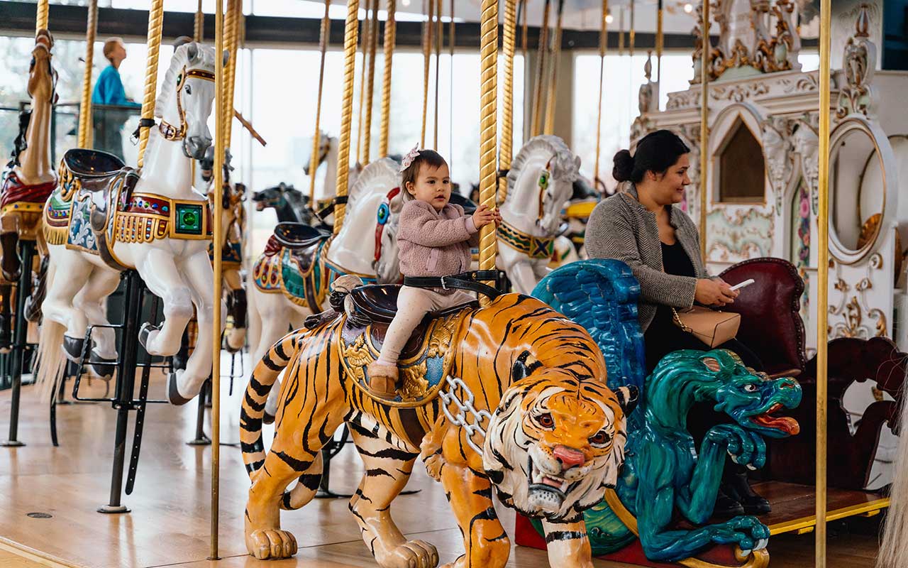A kid and her mom enjoying the Looff Carrousel ride