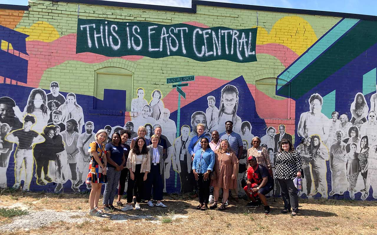 A group of people standing in front of an East Central mral